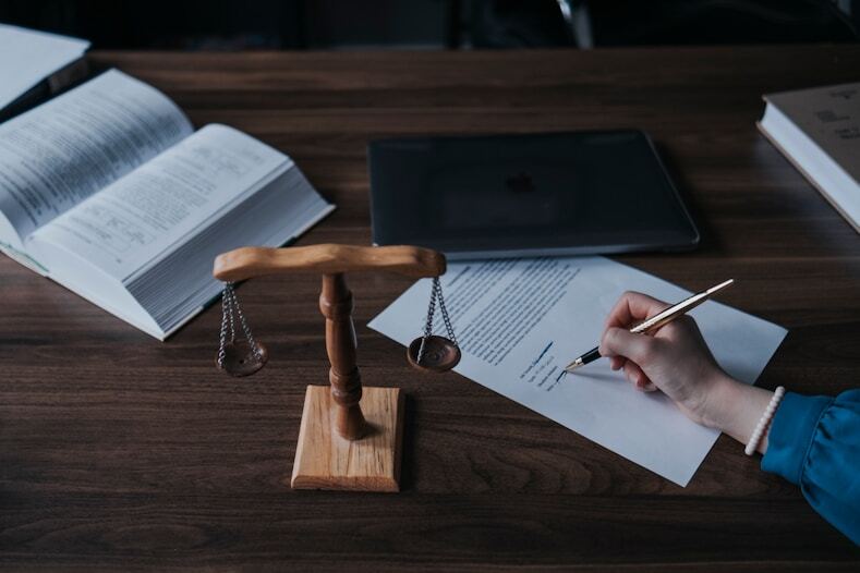 A person signing a document next to a scale of justice