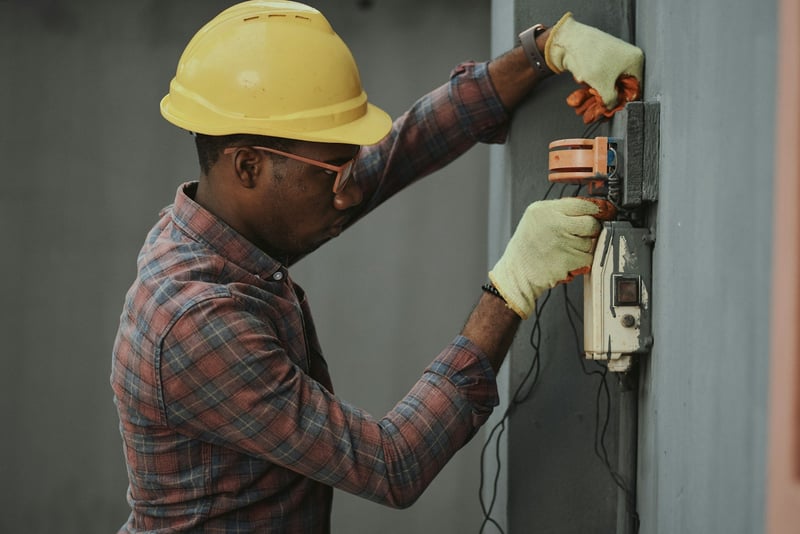 Electrician in a hard hat testing an electrical panel