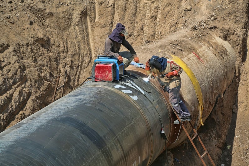 Two pipefitters welding a large pipeline section