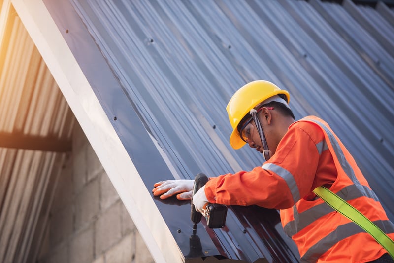 Sheet metal worker in a hard hat installing metal siding