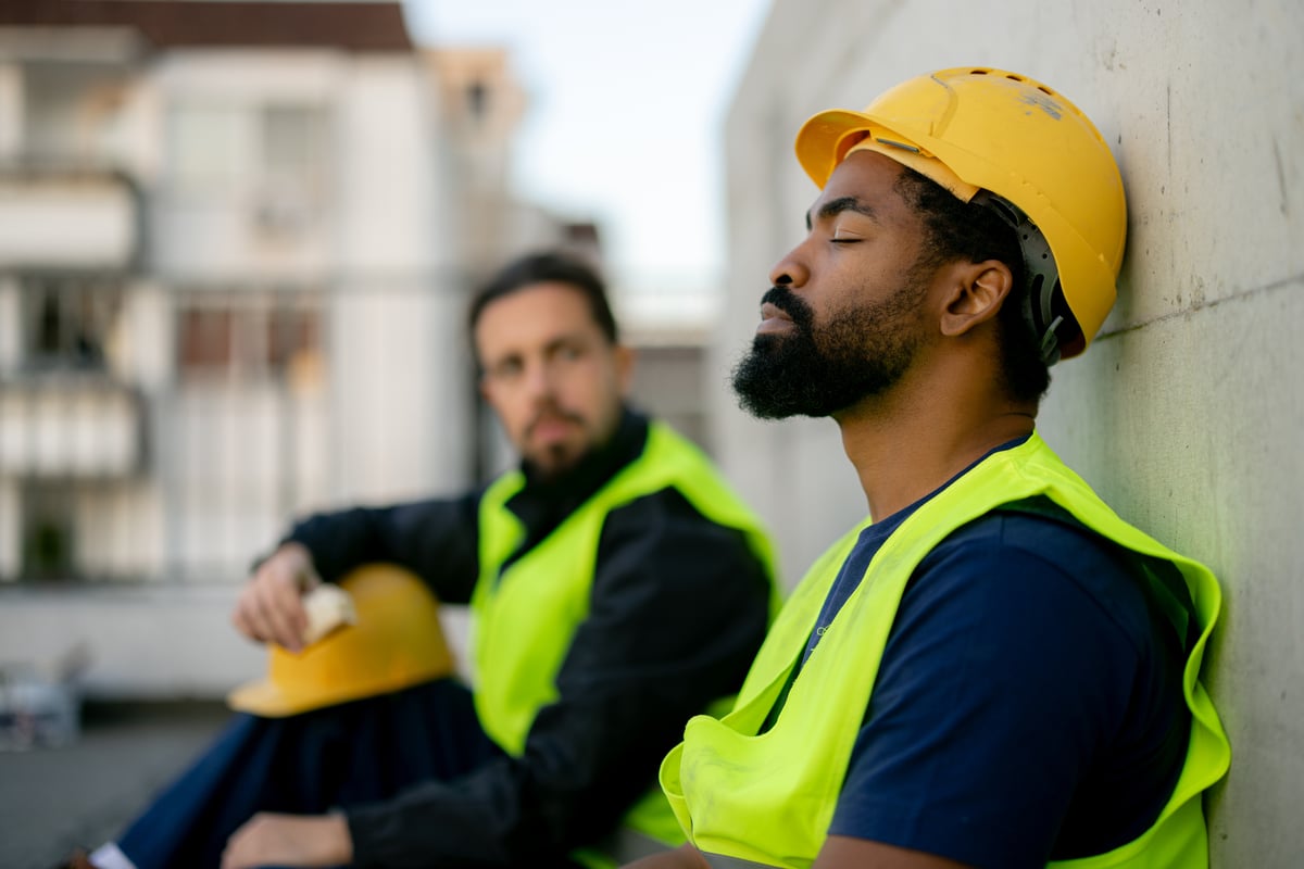 Two tradespeople in safety vests talking on a job site