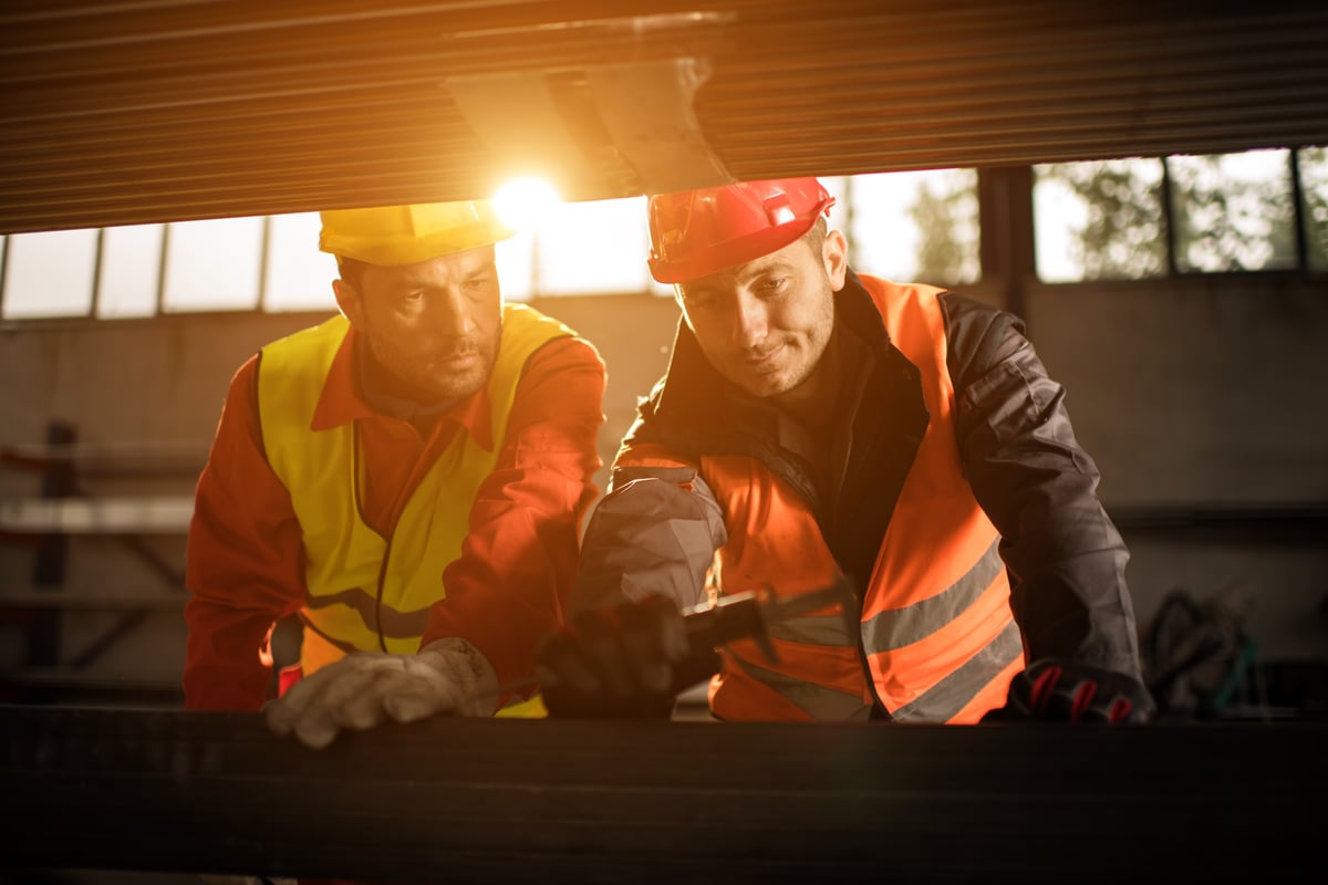 Two tradespeople in hard hats reviewing work together